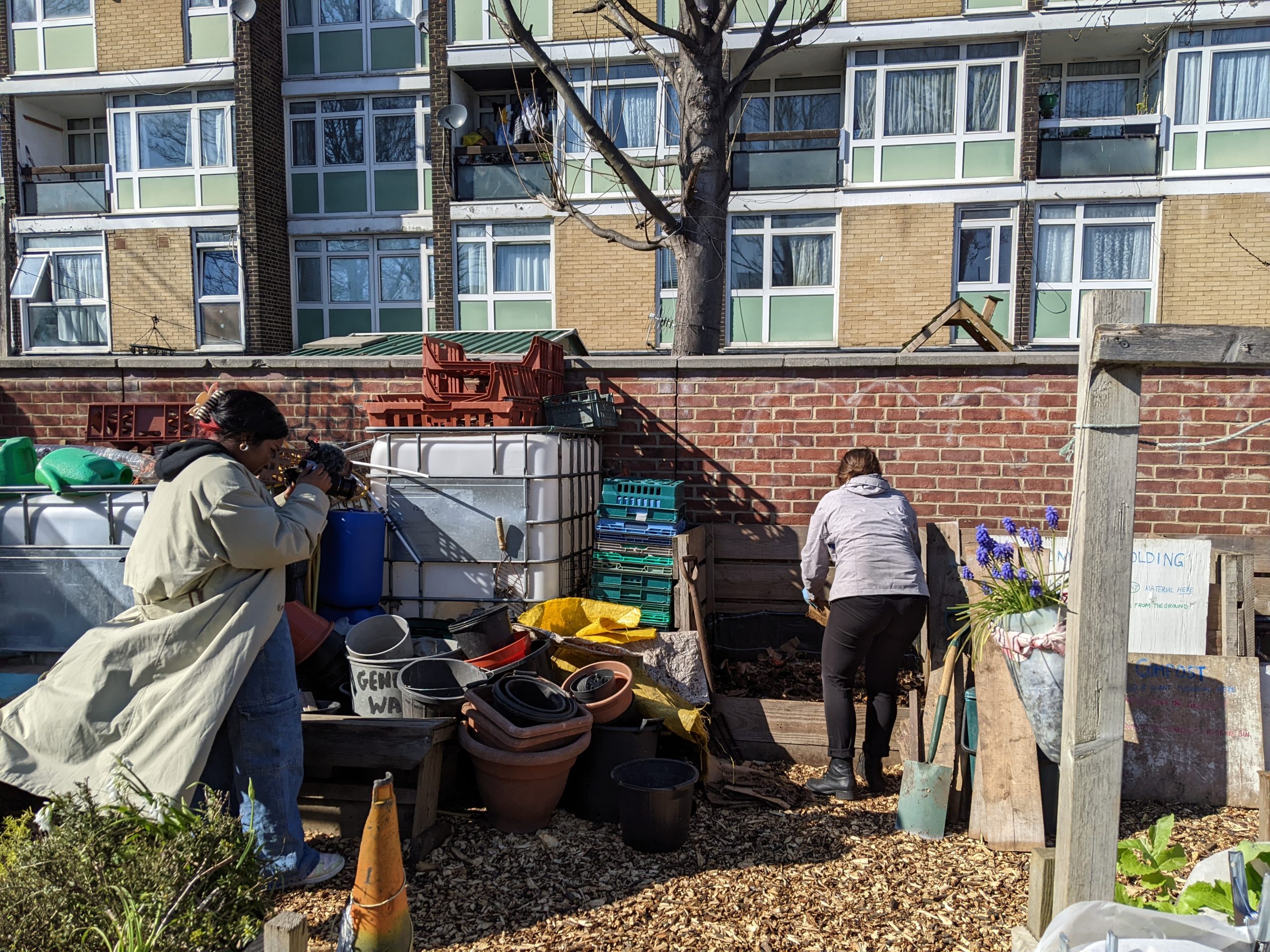 filmaker taking pictures of gardner at the compost heap