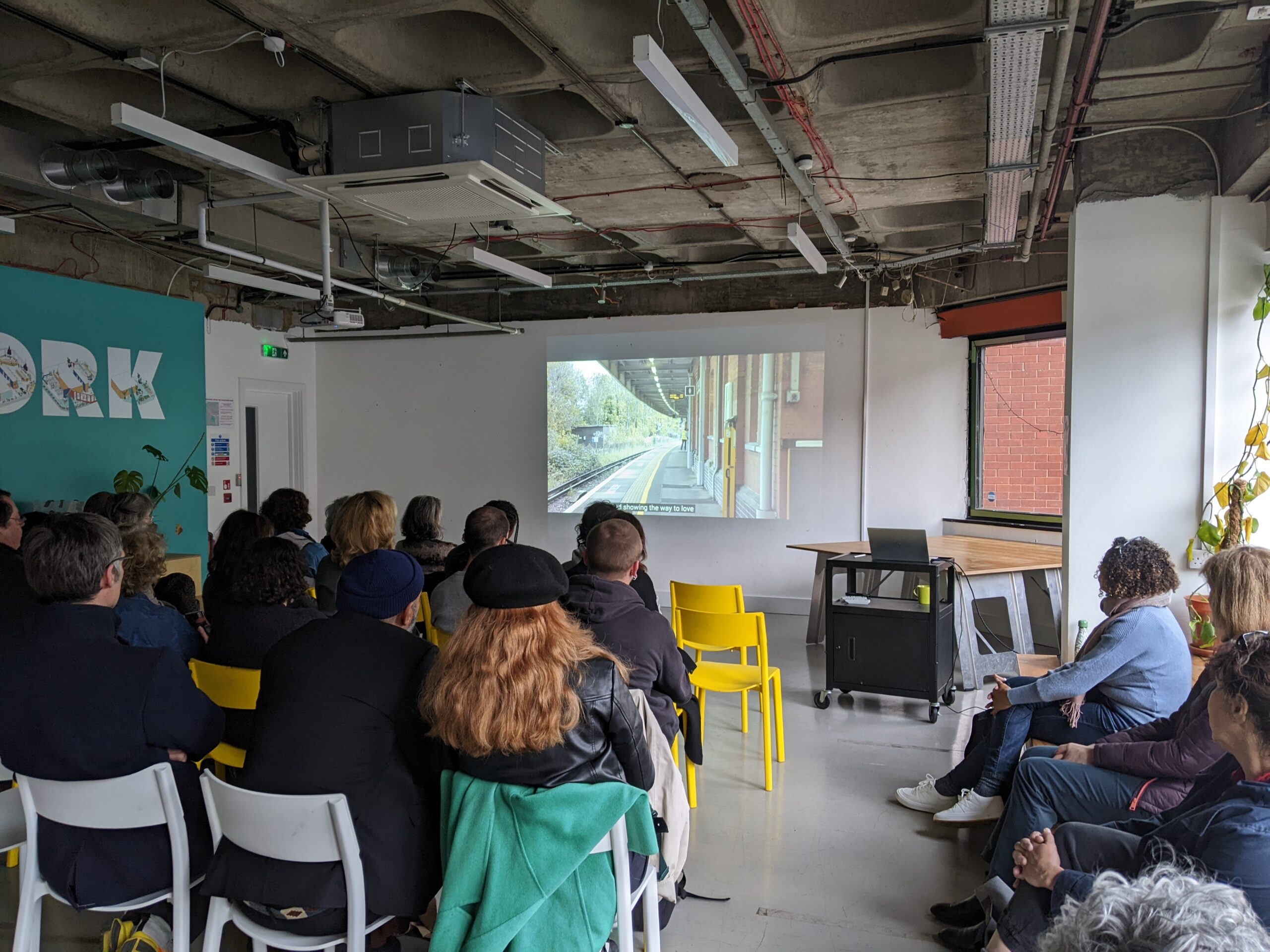 A photograph of people sat watching a screen